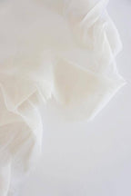 Close-up of warm white silk with folds on a white background