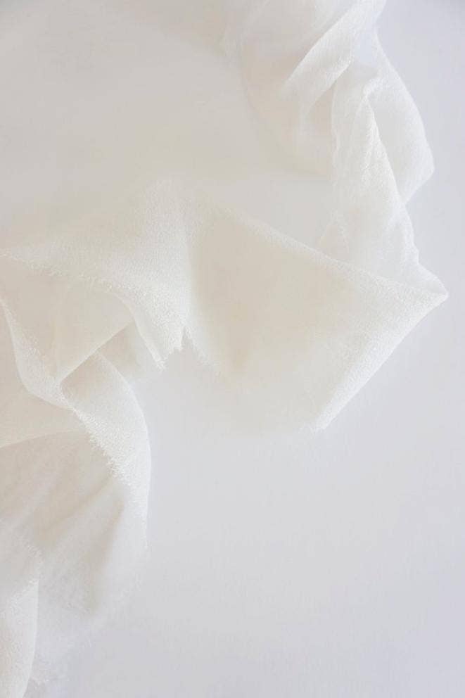 Close-up of warm white silk with folds on a white background